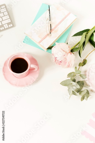 Flat lay women's office desk. Female workspace with laptop, flowers peonies, accessories, notebook, glasses, cup of coffee on white background. Top view feminine background.Copy space