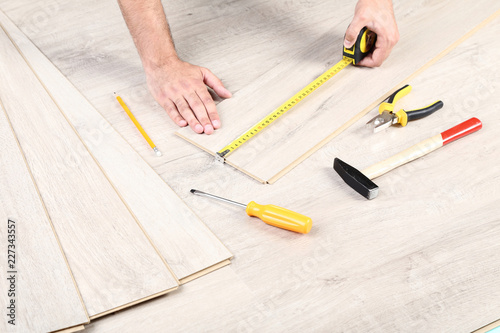 Man installing timber laminate flooring with tools