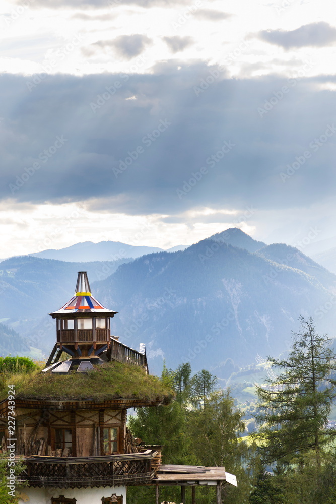 Beautiful sunset with dramatic clouds over Dachstein mountains, wooden lookout with green sod roof in foreground, Northern Limestone Alps, Schladming, romantic love peaceful meditation concept