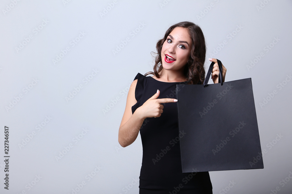 Naklejka premium Happy woman with shopping bag on grey background