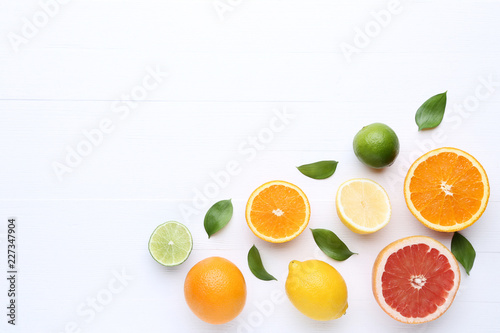 Citrus fruits with green leafs on white wooden table