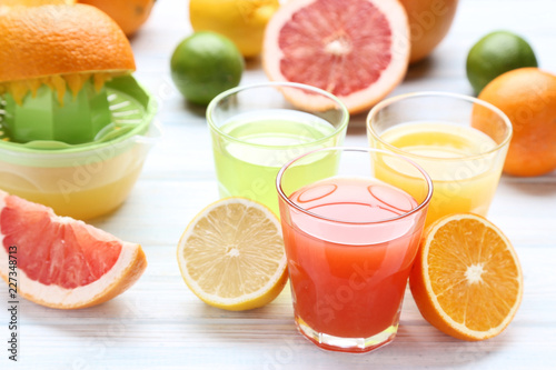 Citrus juice in glasses with fruits on white wooden table