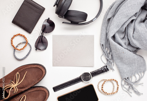 Flat lay of men's accessories with shoes, watch, phone, earphones, sunglasses, scarf over the orange background photo