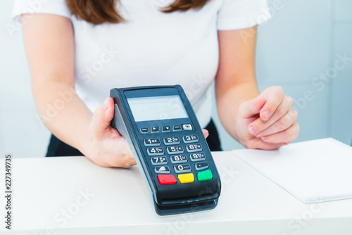 Seller holds payment terminal in hands. Contactless payment with nfc technology at shop, clinic, hotel. Mobile payment PayPass. Selective Focus on hands. Copy space.