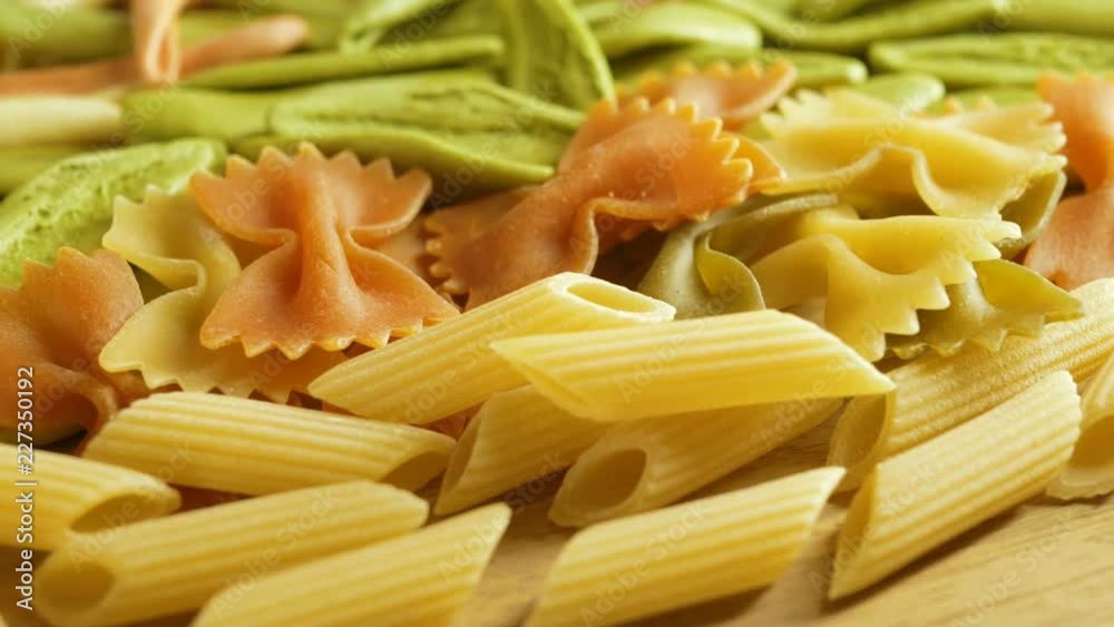 Dried colored italian farfalle pasta, rotate on wooden background Dried colored italian farfalle pasta, rotate on wooden background