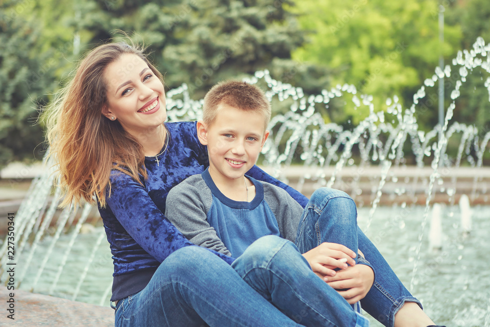 Happy beautiful mother and son enjoying near the fountain Happy beautiful mother and son enjoying near the fountain
