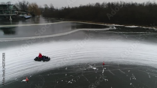 Low altitude aerial footage of ice karts drifting through corner on frozen lake showing the snow dust emerging from slipping wheels typical winters sports activity stable video 4k high resolution photo