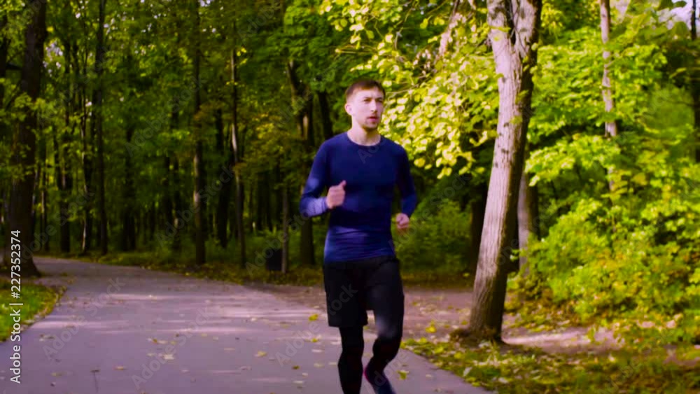 Dolly shot, slow motion. Young man running in the park. Fitness Dolly shot, slow motion. Young man running in the park. Fitness