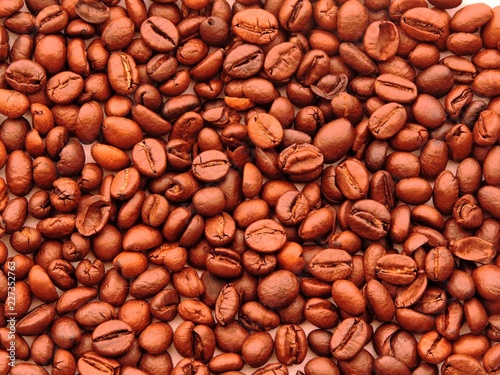 Top view of a dense bunch of roasted coffee beans in variety of reddish brown shades