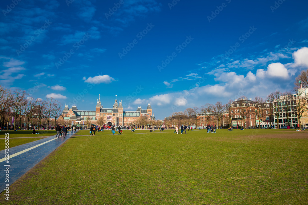 People enjoying a sunny early spring day at  the famous Museum Square next to the National Museum in Amsterdam