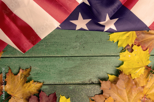 Green vintage wooden background covered with american flag and autumn leaves, copy space