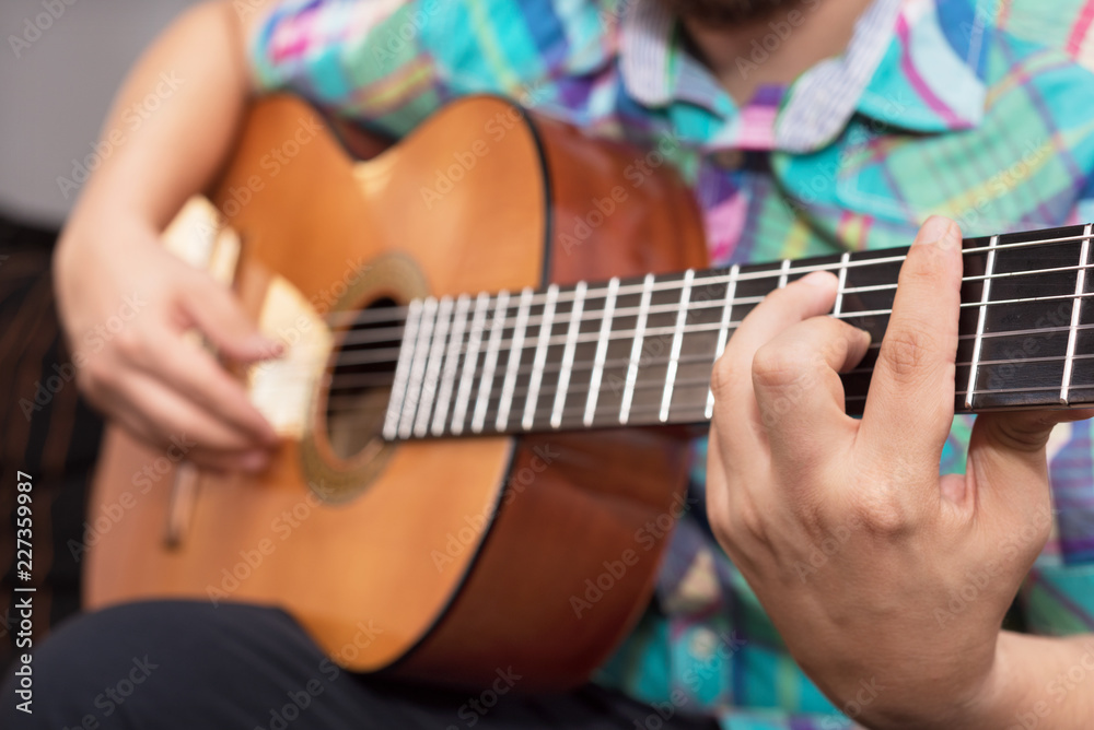 Fototapeta premium Bearded hipster man hand playing acoustic guitar. Close-up selective focus on hand.