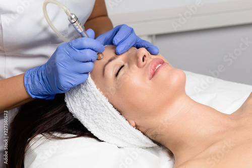 Beautiful woman getting facial microdermabrasion peeling treatment at luxury cosmetic beauty spa clinic. Exfoliation, rejuvenation and hydratation. Cosmetology concept. photo