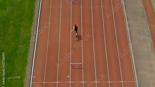 Female athletic jumping over hurdle on sports track 4k