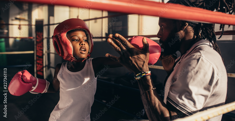 Fototapeta premium Boy practicing box with coach in boxing ring