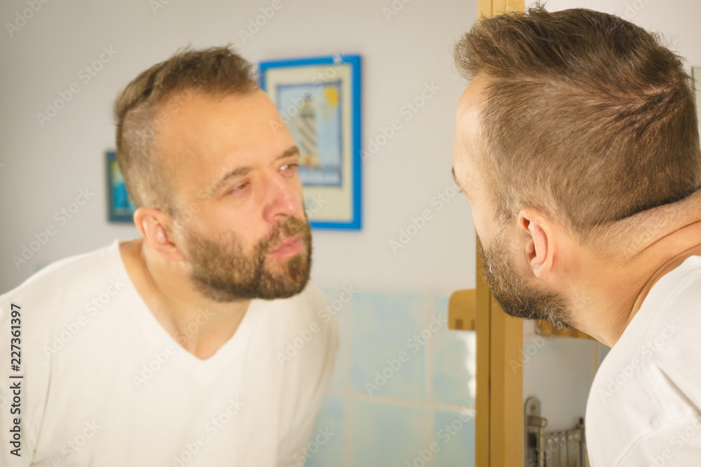 Fototapeta premium Man looking at himself in mirror