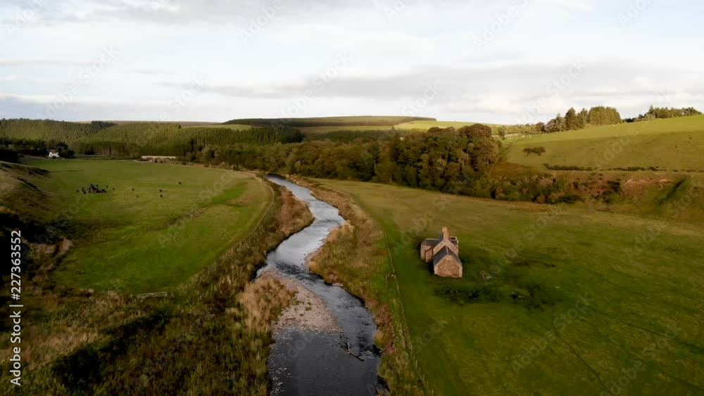 Aerial-Flying over beautiful clear stream passing stone cottage with the lovely sunset light of golden hour casting a warm glow over the entire scene in the peaceful English countryside Aerial-Flying over beautiful clear stream passing stone cottage with the lovely sunset light of golden hour casting a warm glow over the entire scene in the peaceful English countryside