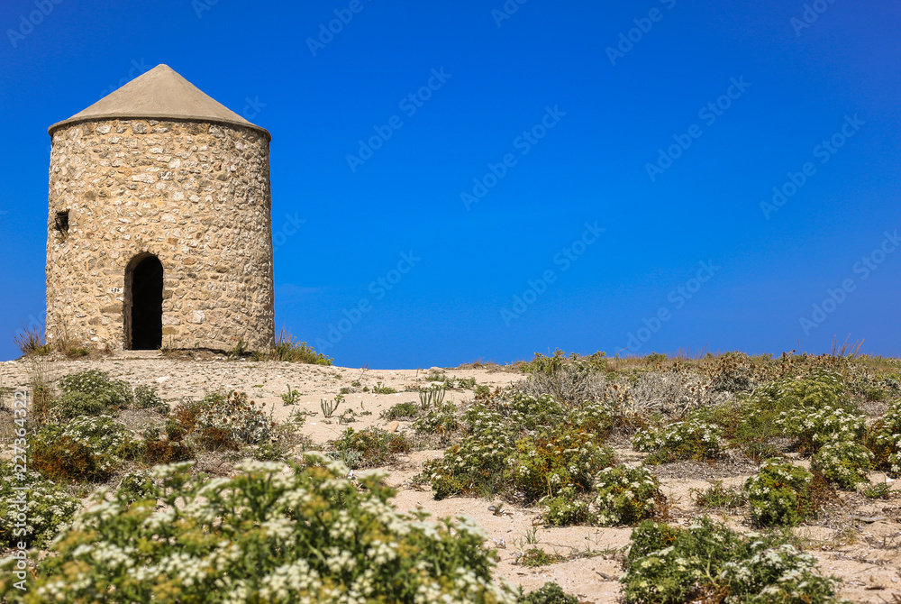 Old windmill in blue sky. The old windmill is located on Gira beach, Lefkada Island, Greece