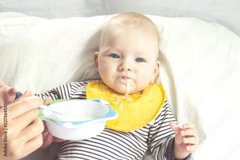 Young mother feeds a small child with a spoon. Concept of starting feeding baby solid food Young mother feeds a small child with a spoon. Concept of starting feeding baby solid food