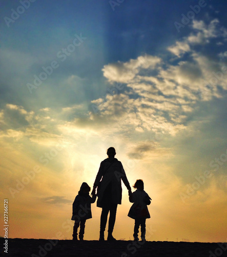 Parent and Two Children Looking at Sunset © Kimberly