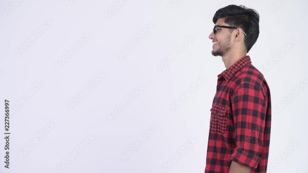 Profile view of young happy bearded Indian hipster man smiling