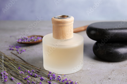 Fototapeta Naklejka Na Ścianę i Meble -  Bottle with natural herbal oil and lavender flowers on table against blurred background