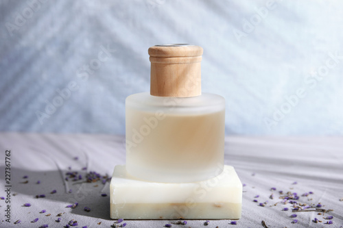 Fototapeta Naklejka Na Ścianę i Meble -  Bottle with natural lavender oil and soap on table against blurred background
