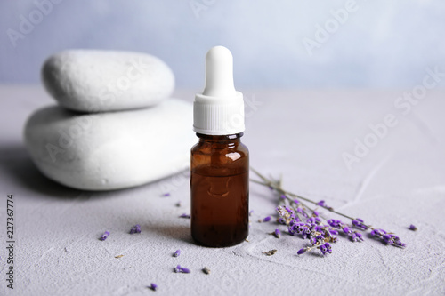 Fototapeta Naklejka Na Ścianę i Meble -  Natural herbal oil and lavender flowers on table against blurred background