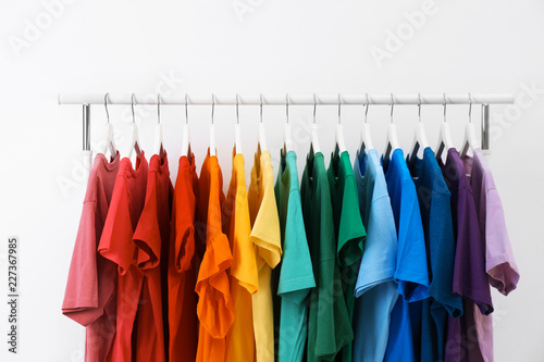 Rack with bright clothes on white background. Rainbow colors