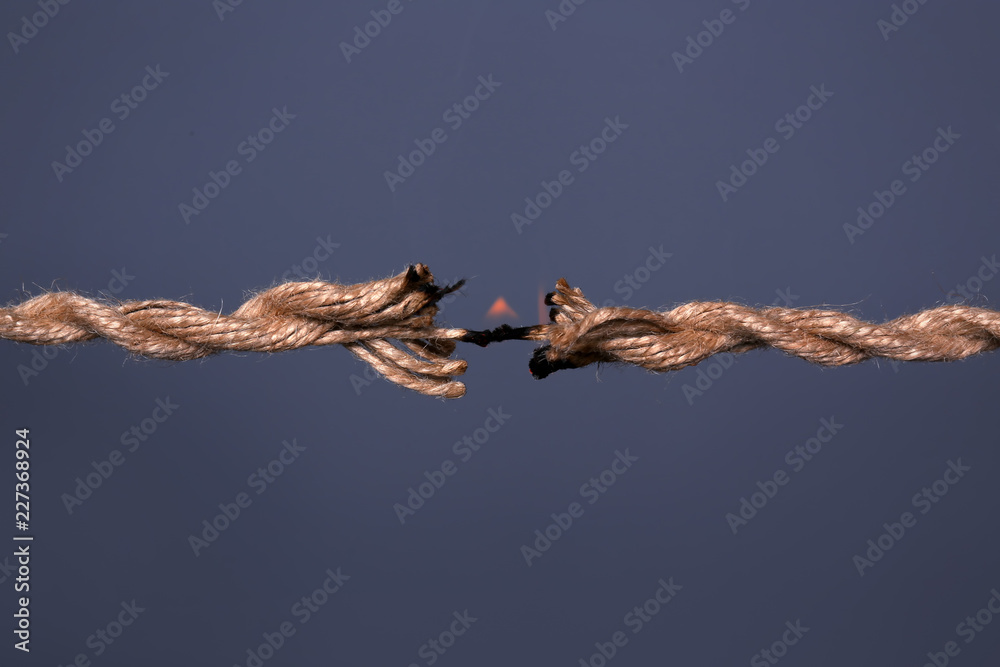 Burning rope at breaking point on dark background, closeup