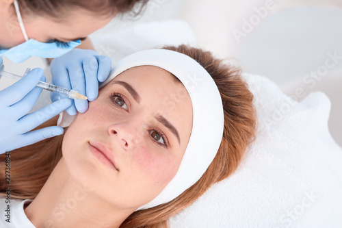 Woman undergoing face biorevitalization procedure in salon. Cosmetic treatment photo