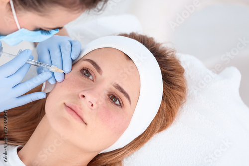 Woman undergoing face biorevitalization procedure in salon. Cosmetic treatment