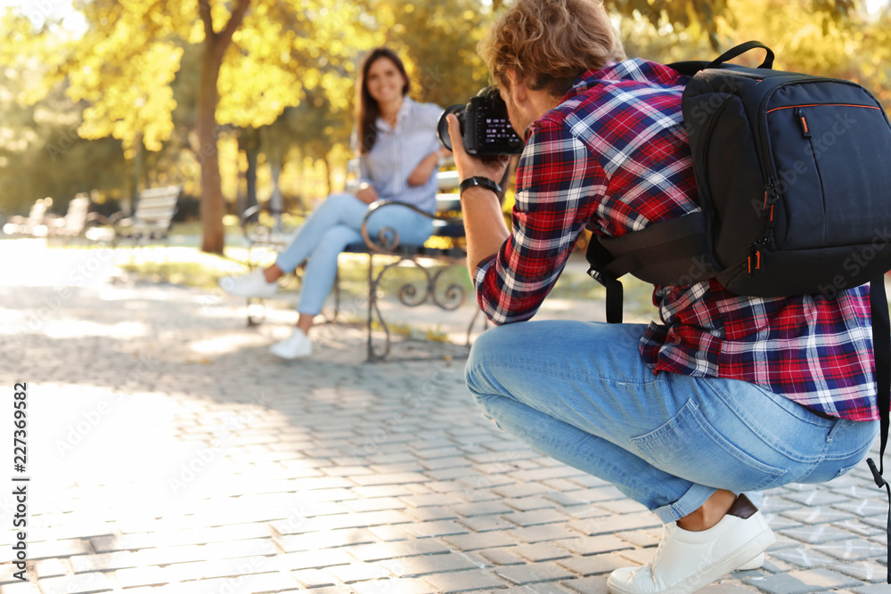 Young male photographer taking photo of model with professional camera in park Young male photographer taking photo of model with professional camera in park