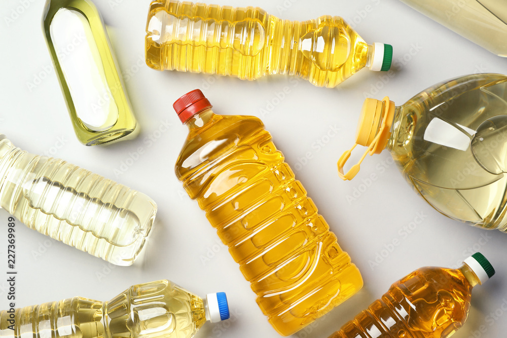 Naklejka premium Bottles of oils on light background, top view