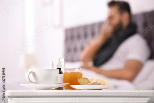 Hot tea with cough remedies and ill man on background