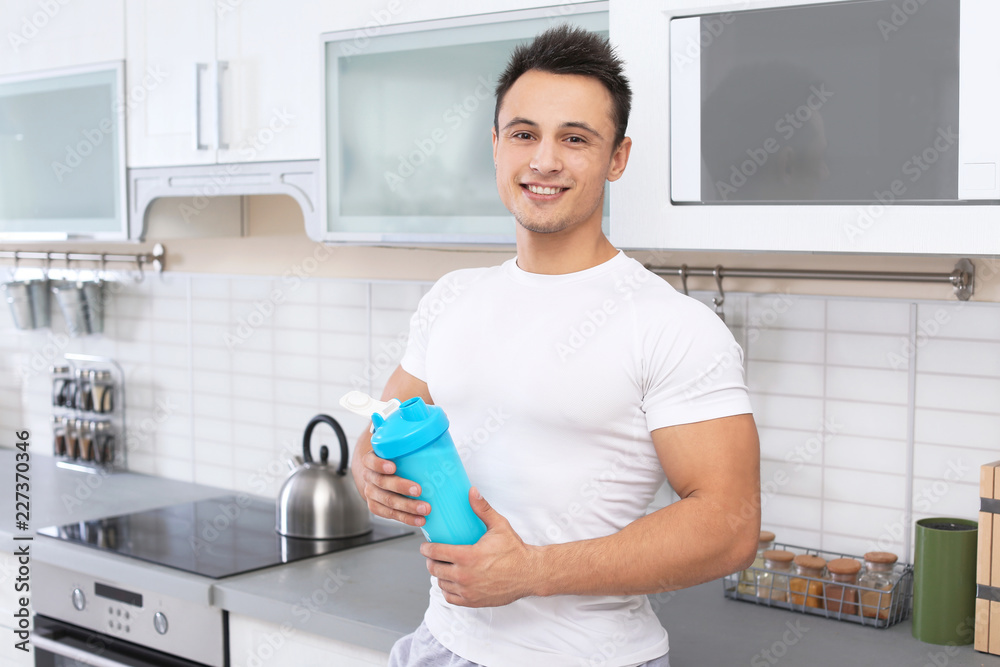 Man with bottle of protein shake in kitchen Man with bottle of protein shake in kitchen