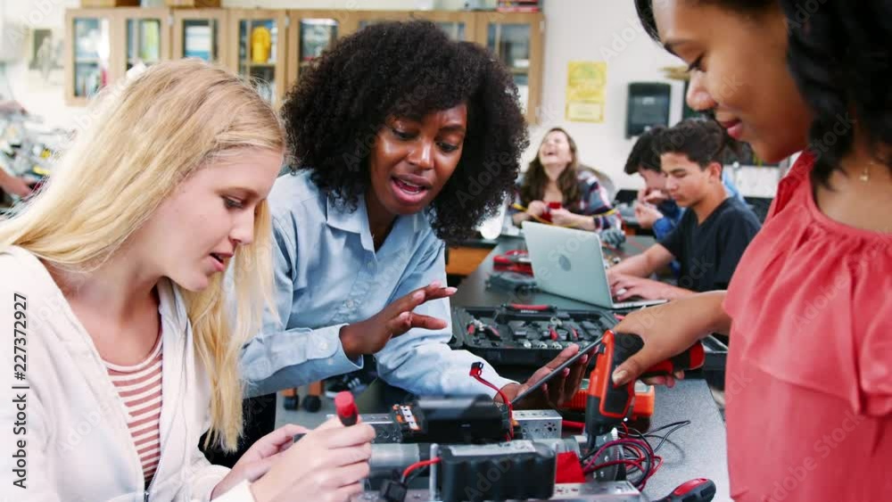 High School Teacher With Female Pupils Building Robotic Vehicle In Science Lesson