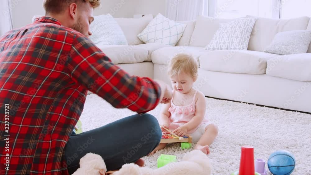 Dad and toddler daughter playing instruments in sitting room