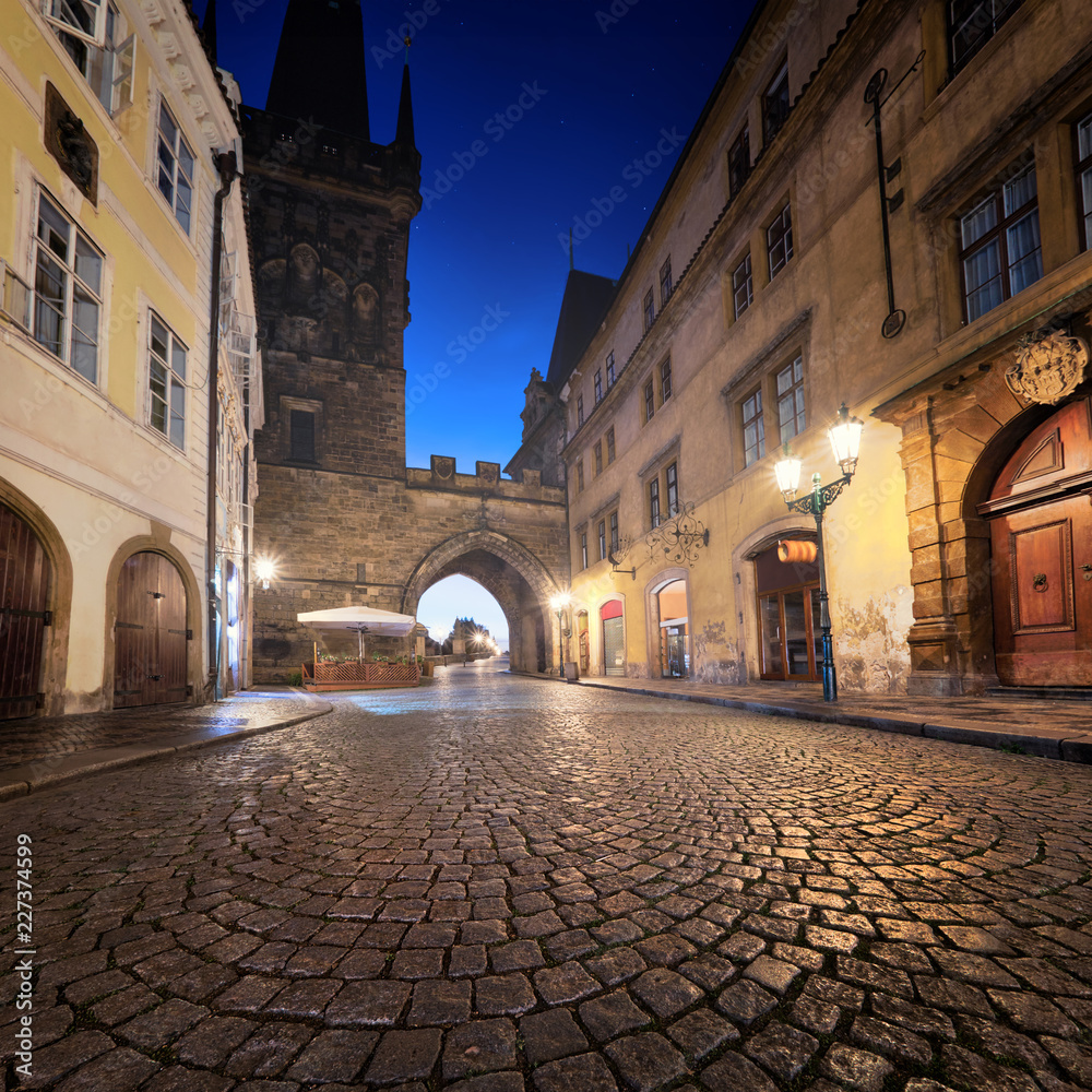 Fototapeta Średniowieczna ulica prowadząca w kierunku Charles Bridge Tower w deszczową noc w Pradze
