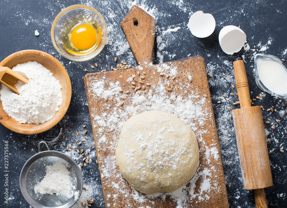 Baking ingredients. Bowl, eggs, flour, eggbeater, rolling pin and eggshells on black chalkboard from above. Baking ingredients. Bowl, eggs, flour, eggbeater, rolling pin and eggshells on black chalkboard from above.
