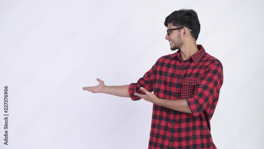 Young happy bearded Indian hipster man showing something Young happy bearded Indian hipster man showing something