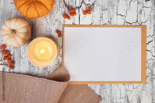 Autumn decorations: pumpkins, napkin and berries on rustic table, and a white block note, top view, space