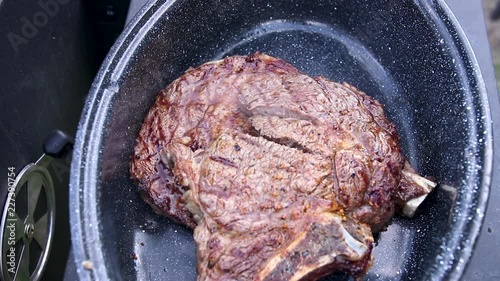 View from top serving juicy and tasty looking steak into enamel casserole with a slow zoom in effect. photo