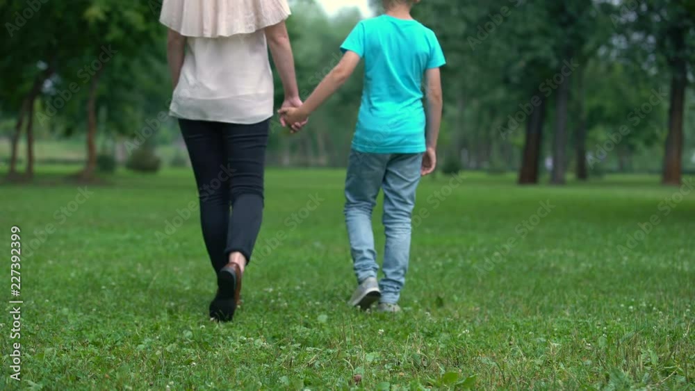 Mother and son holding hands, walking away together, concept of child adoption