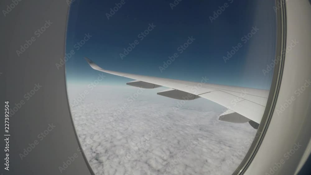 Aerial view. Looking out through an airliner window during daytime. View of an airplane wing high above clouds over North America en route from Denver, United States to Munich, Germany.