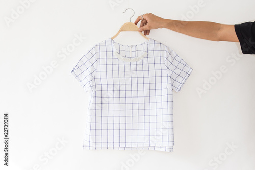 Hand holding White blouse is clothes hanging on white background.