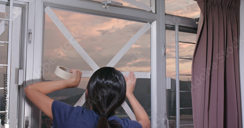 Tableau sur toile Woman stick tape on window to prevent typhoon
