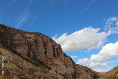 Echo Canyon , Utah Beautiful rock cliffs and blue sky, small shrubs and bushes along the hillside leading to the cliff face.  photo