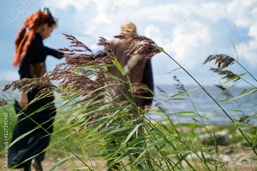 blurry image  behind the stems of the cane  a man takes a woman somewhere  taking her by the hand