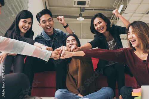 Young successful businesspeople are fist bumping after working hard at new project